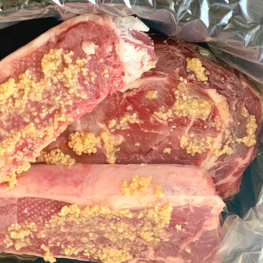 raw steak topped with garlic in slow cooker