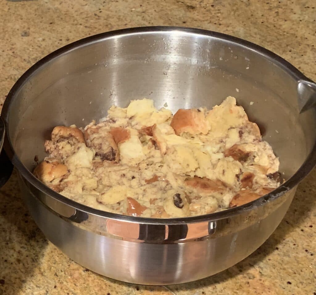 Bread and egg mixture in a metal bowl read to rest prior to cooking.