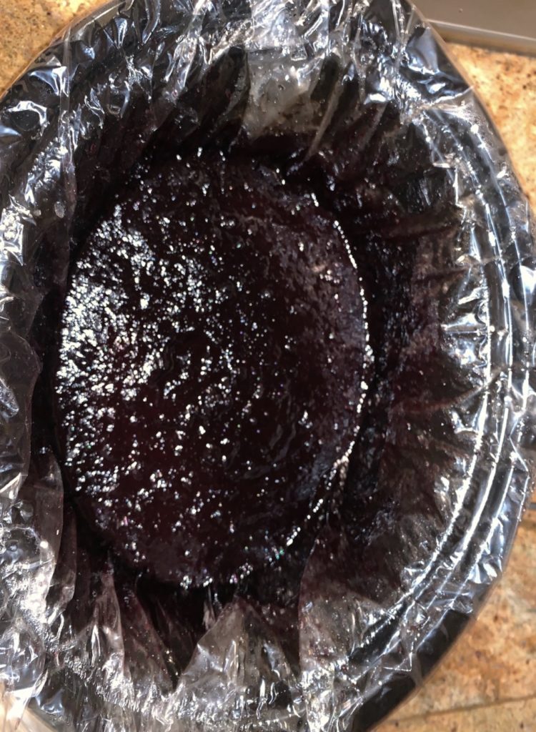 top view of a slow cooker with cooked blueberry sauce inside