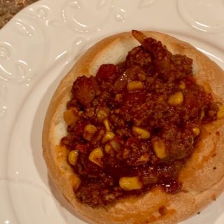 chili in a bread bowl on a white plate
