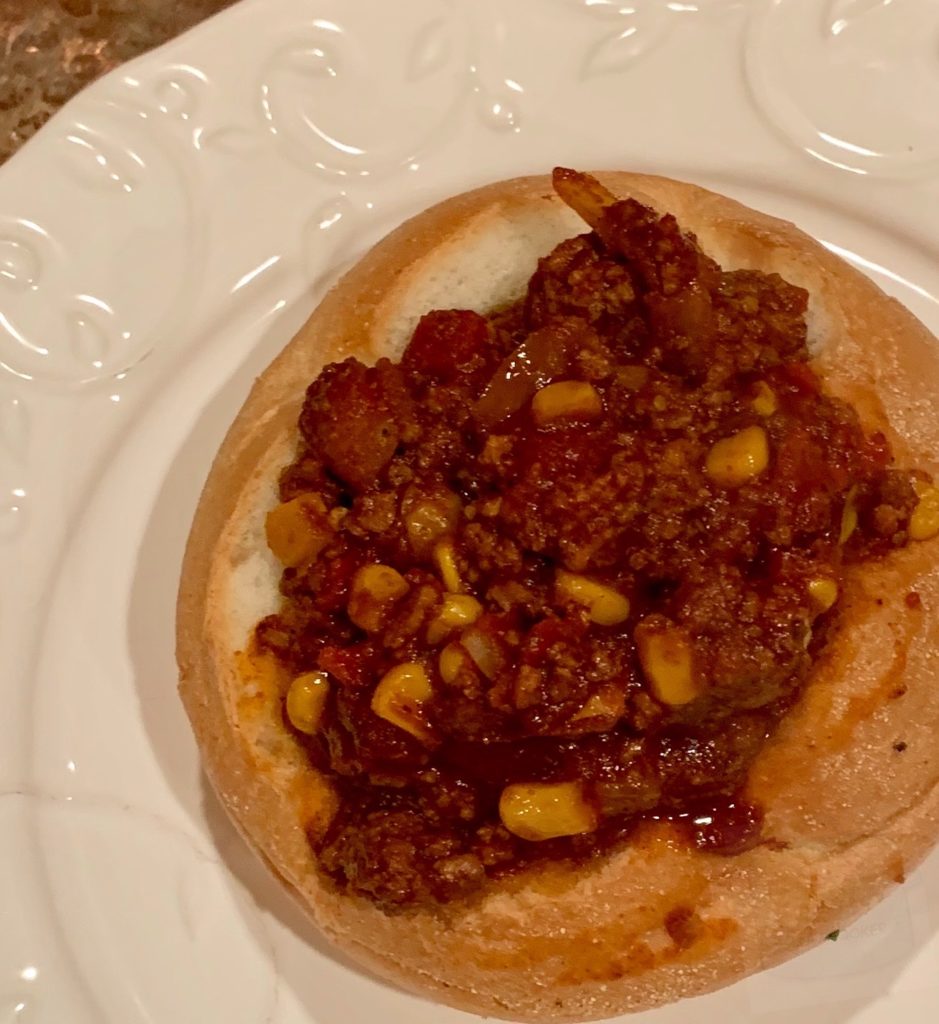 chili in a bread bowl on a white plate