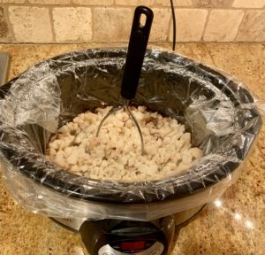 Cooked cauliflower in a slow cooker with a mashed