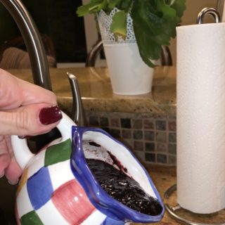 blueberry sauce being poured out of a small pitcher