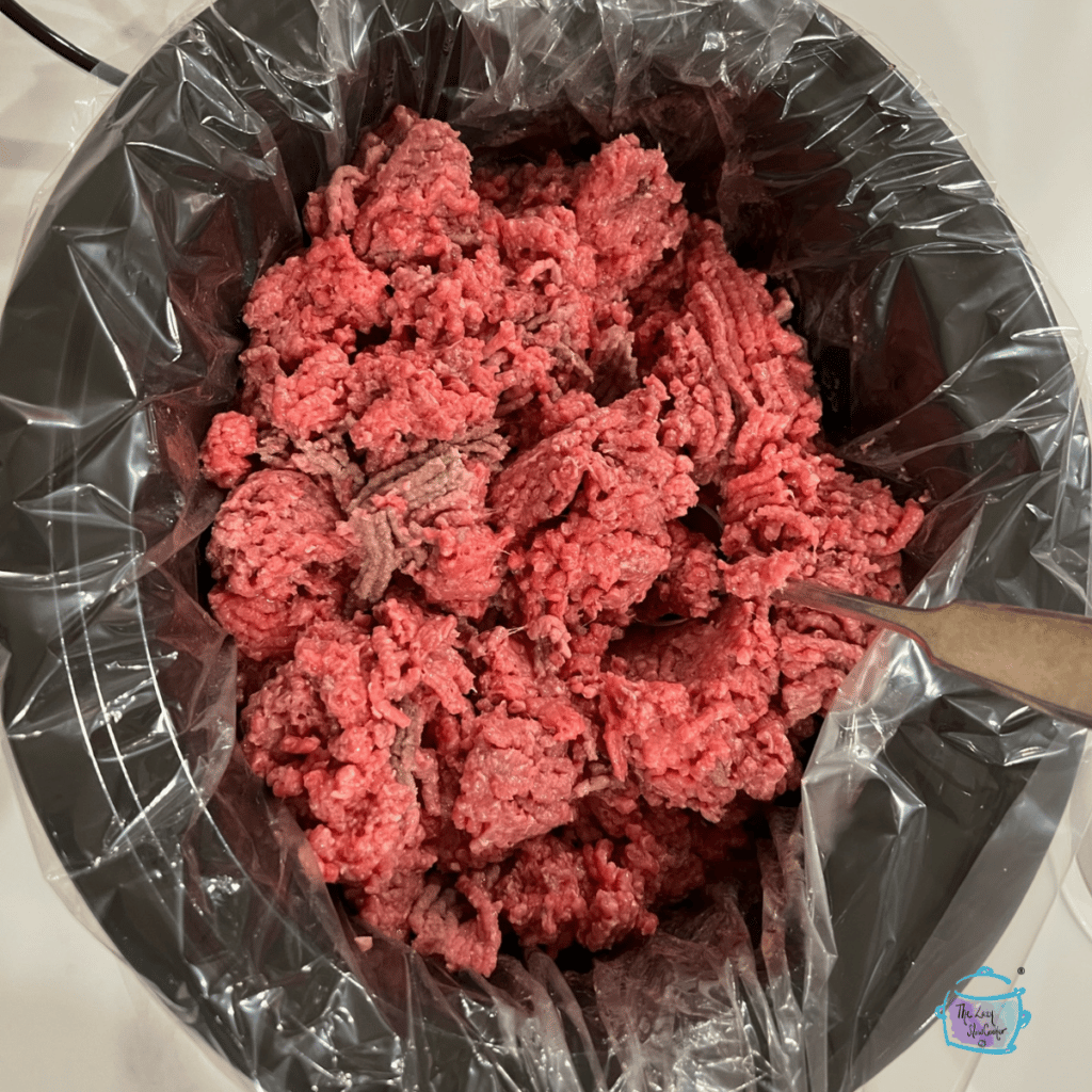 partially cooked ground beef in a slow cooker with a liner