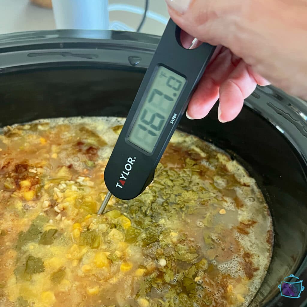 thermometer in chicken that is in slow cooker showing that the proper temperature has been reached