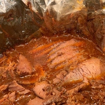 Sliced cooked brisket in slow cooker waiting to be served