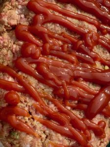 raw meat loaf with ketchup drizzles on top