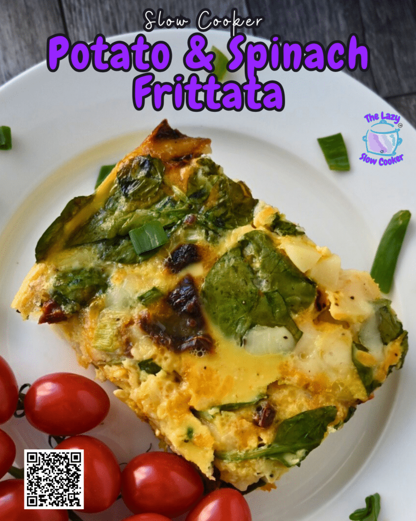 A slice of vegetable frittata with spinach on a white plate, garnished with green onion and served with a bunch of grape tomatoes. The plate is on a rustic wooden surface.