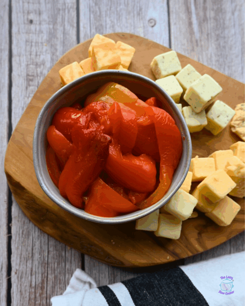 roasted red peppers in a bowl on a cheese board