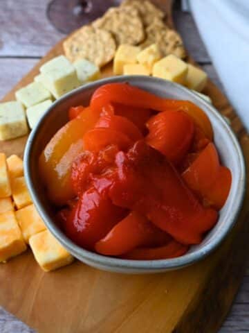 roasted red peppers in a bowl on a cheese board