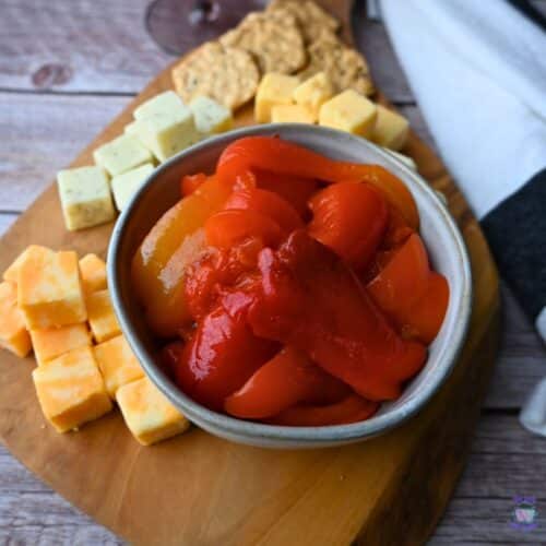 roasted red peppers in a bowl on a cheese board