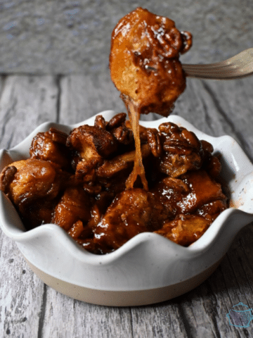 a white wavy bowl with slow cooker gooey caramel sticky bun casserole