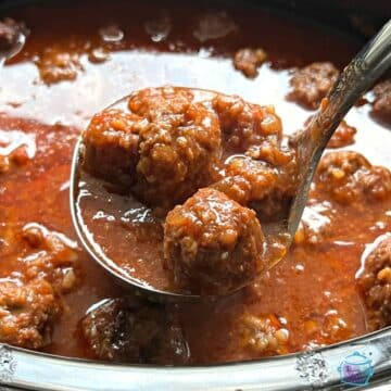 sweet and slow meatballs in slow cooker after cooking. some on a ladel.