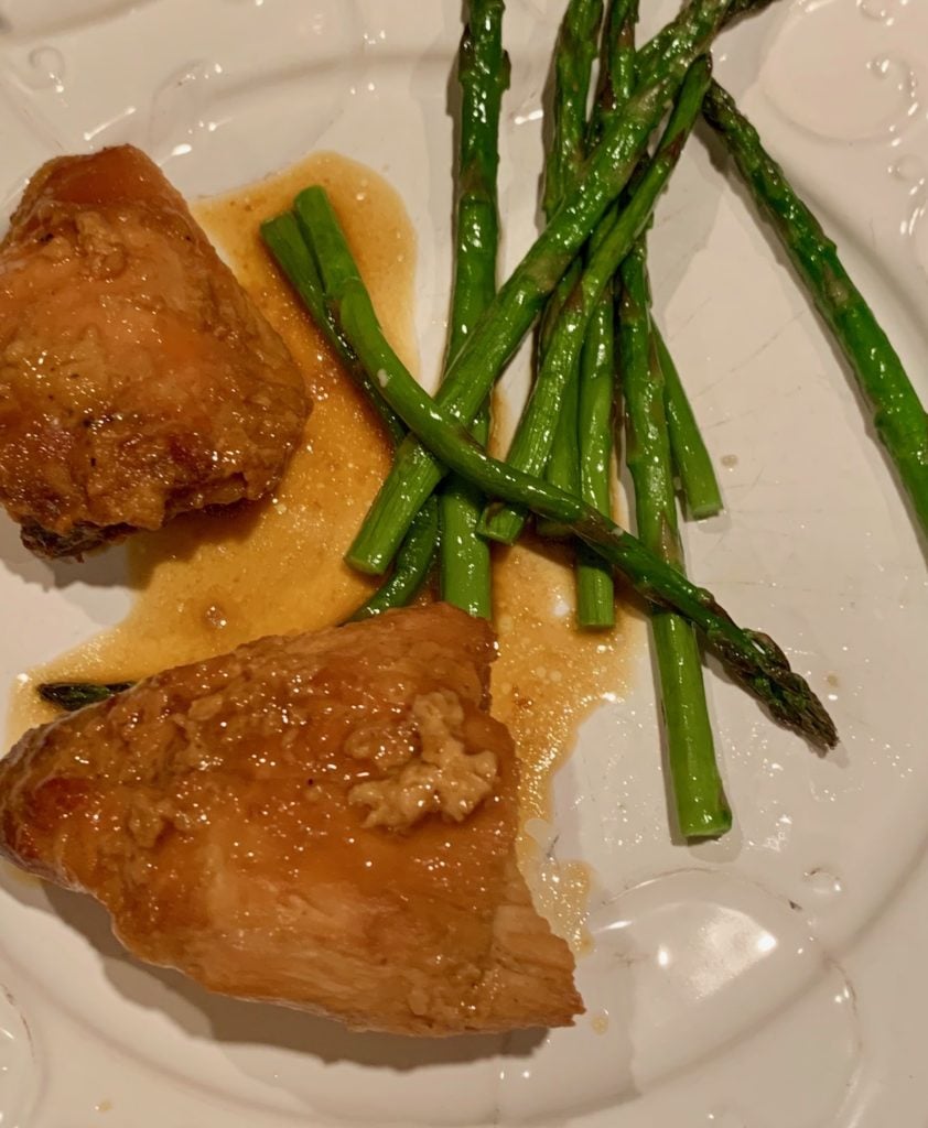Two pieces of honey mustard chicken on a plate with asparagus