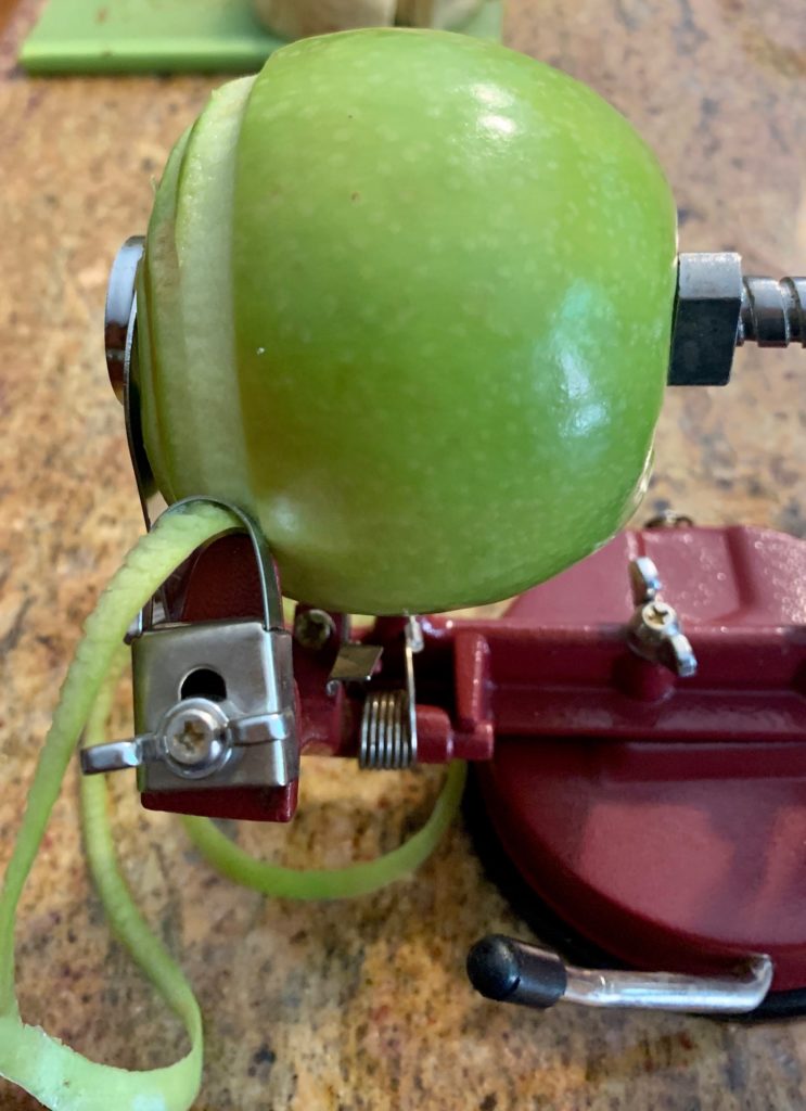 Apple half peeled on peeler