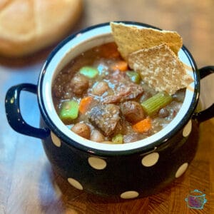 A black bowl with white dots filled with beef stew