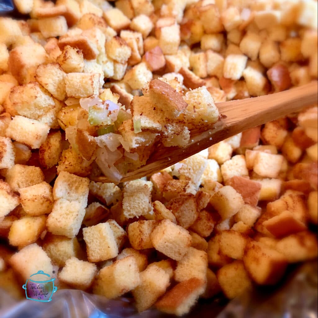 Uncooked stuffing held on a wooden spoon over a pot of stuffing