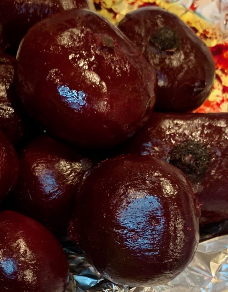 whole roated, peeled beets on foil with a bit of olive oil laying beneath them