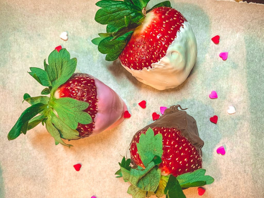 chocolate dipped strawberries with candy hearts sprinkled around