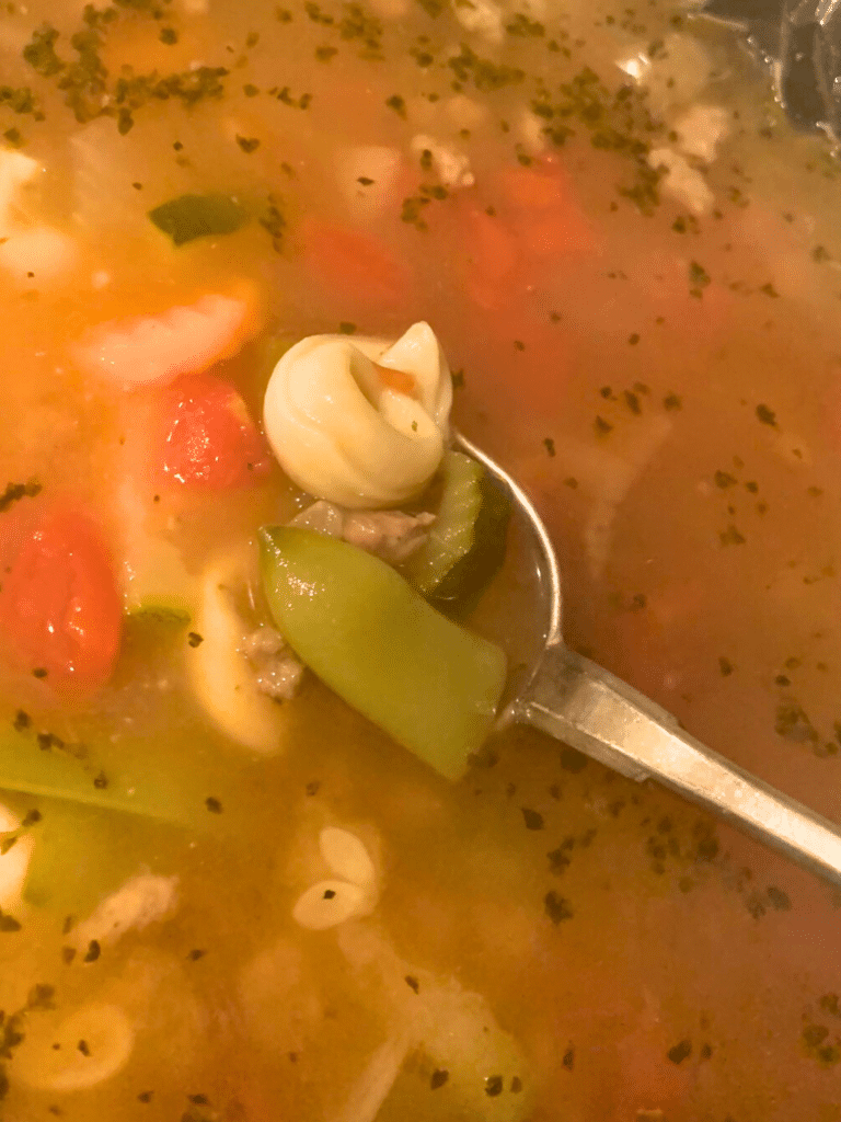 tortellini, veggies and broth on a spoon