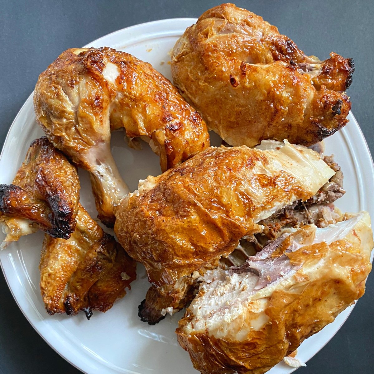 Cut up whole cooked chicken on a white plate