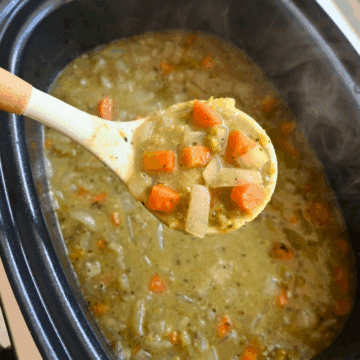 Pea soup in a crockpot with a ladle full of the same in the foreground