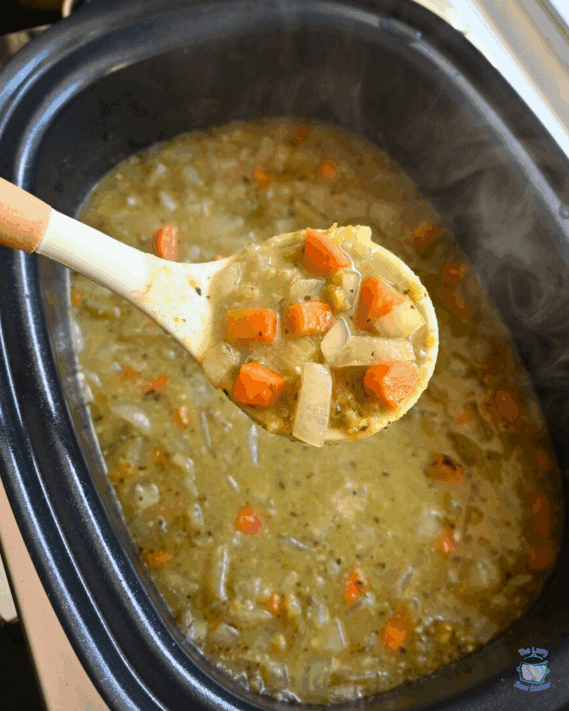 Pea soup in a crockpot with a ladle full of the same in the foreground