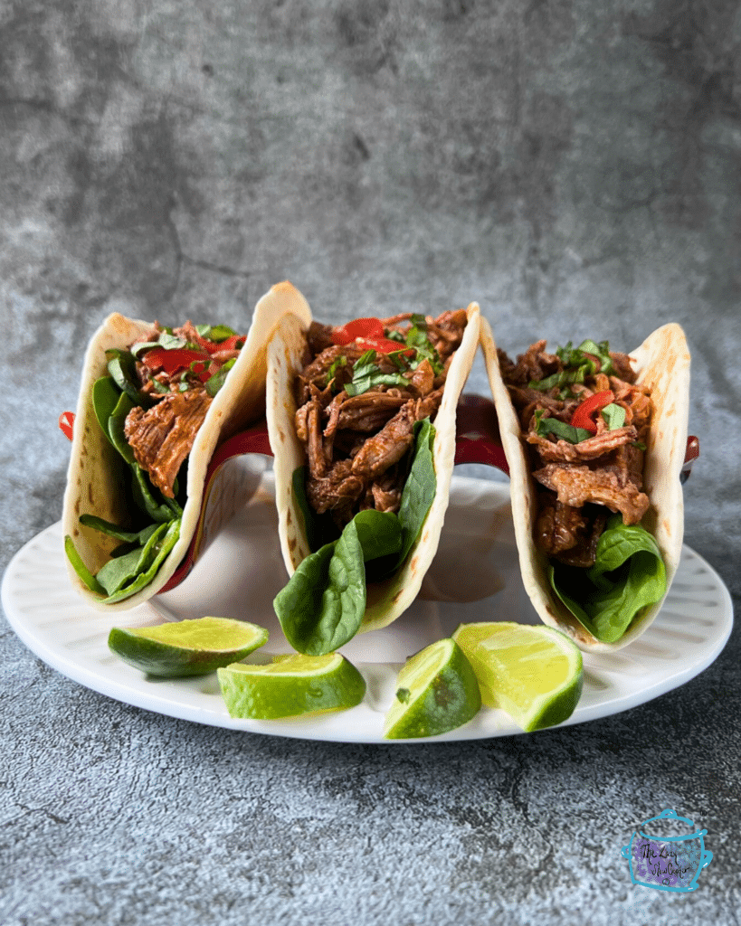 three soft taco shells filled with shredded beef and taco toppings