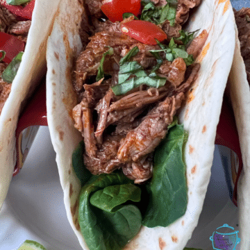 A soft taco shell filled with shredded beef and taco toppings