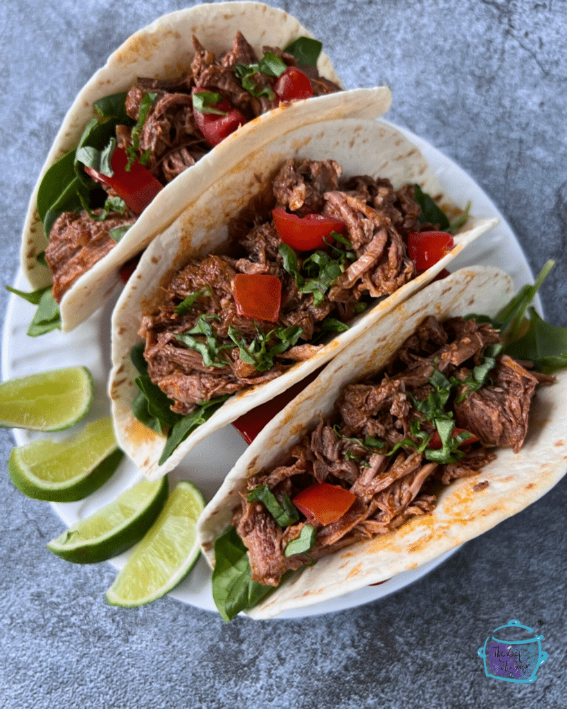 three soft taco shells filled with shredded beef and taco toppings