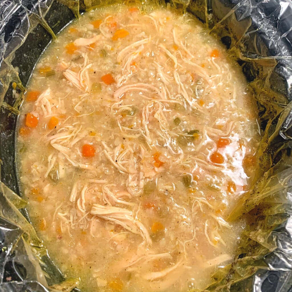 Top view of a crockpot filled with cooked chicken soup with veggies