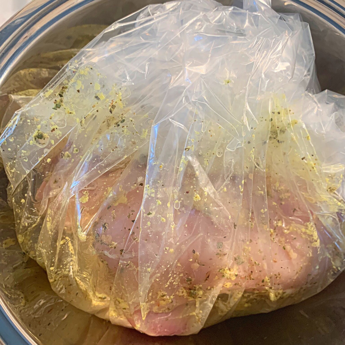 Raw chicken in a slow cooker liner which is doubling as a marinating bag