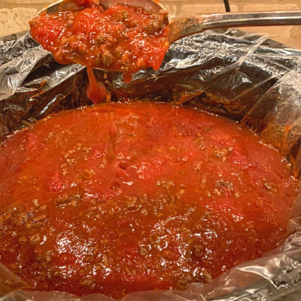 a large spoon held over a crockpot contents  not yet cooked