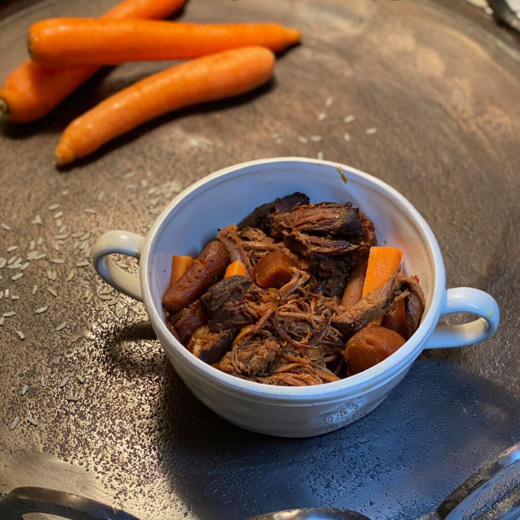 Top view of shredded beef and veggies in a round white bowl