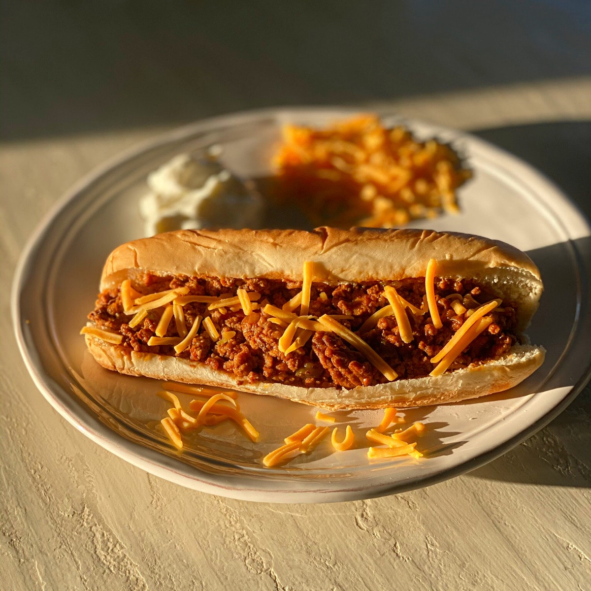 finished sandwich on a long roll sprinkled with shredded cheese