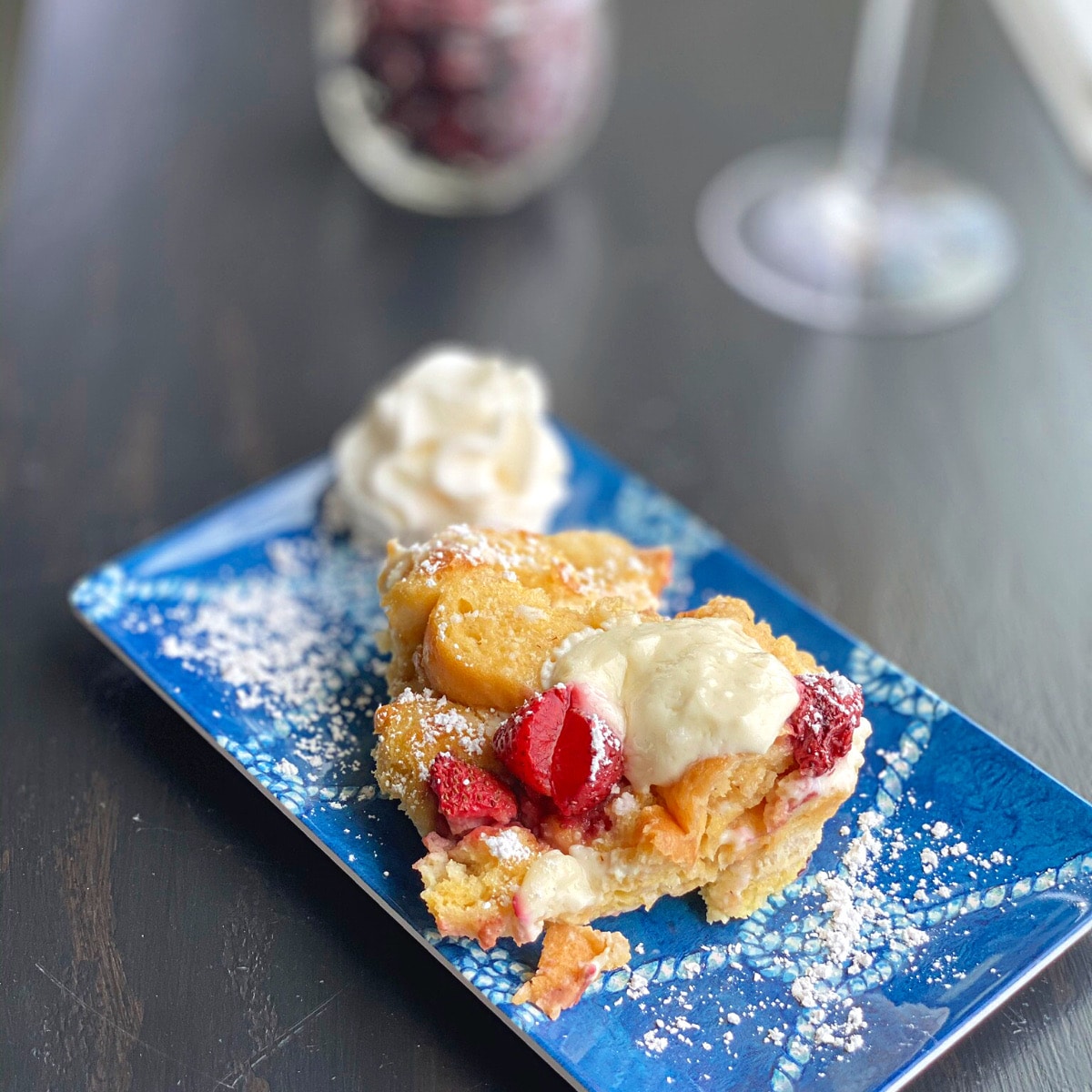 French toast on a blue rectangular plate with one dollop of wipped cream
