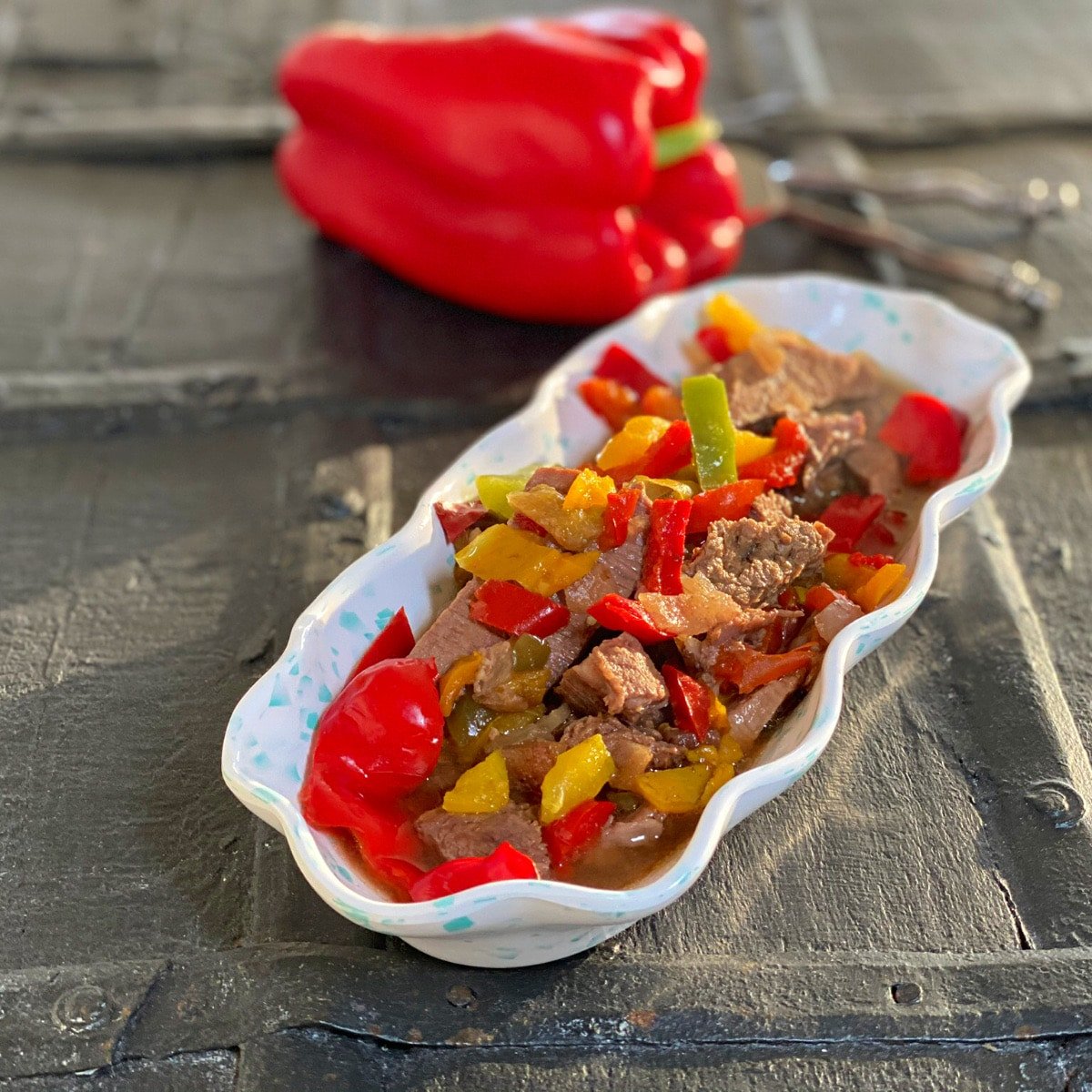 side view of finished pepper steak with a whole red pepper in background