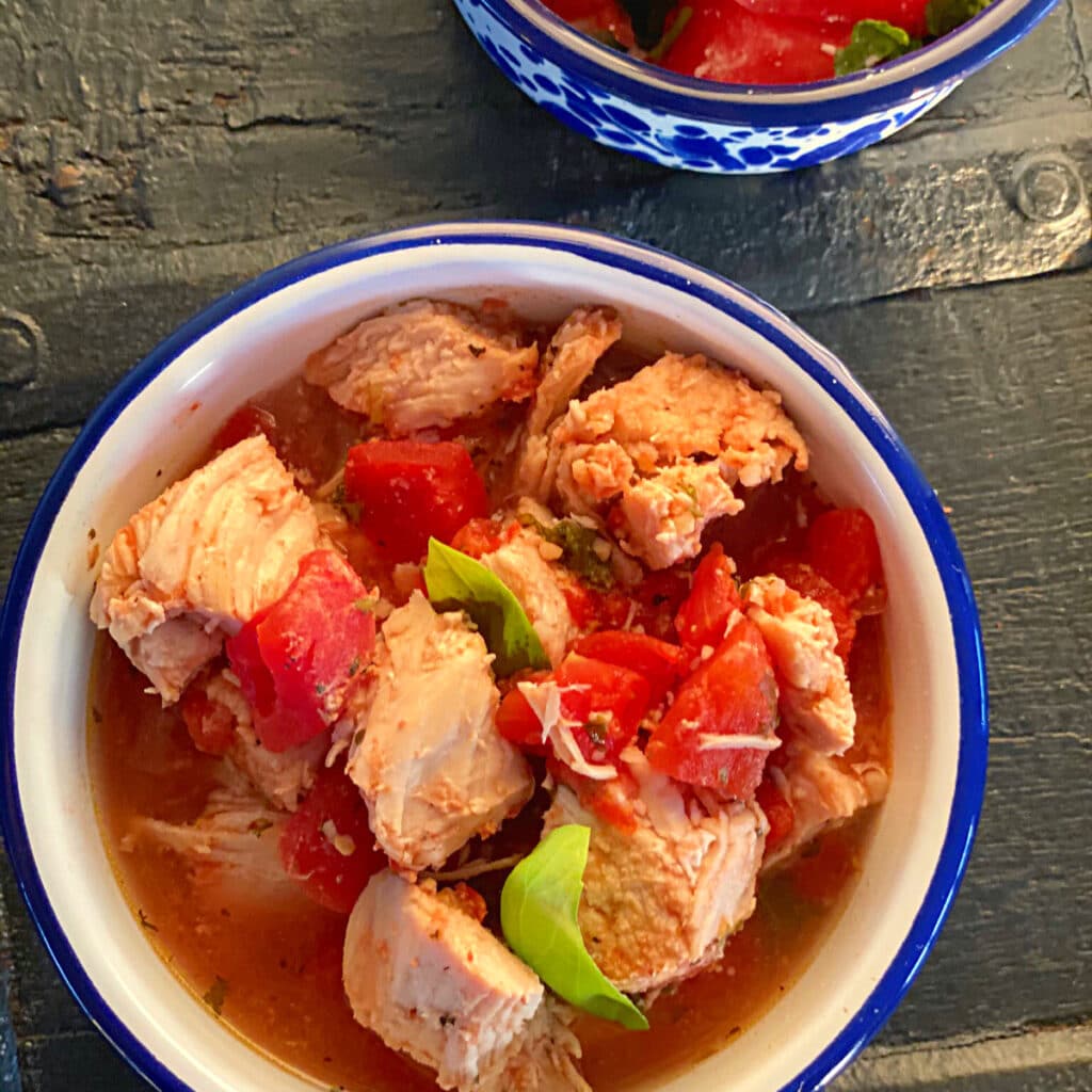 close up view of chicken, tomatoes and basil after cooking