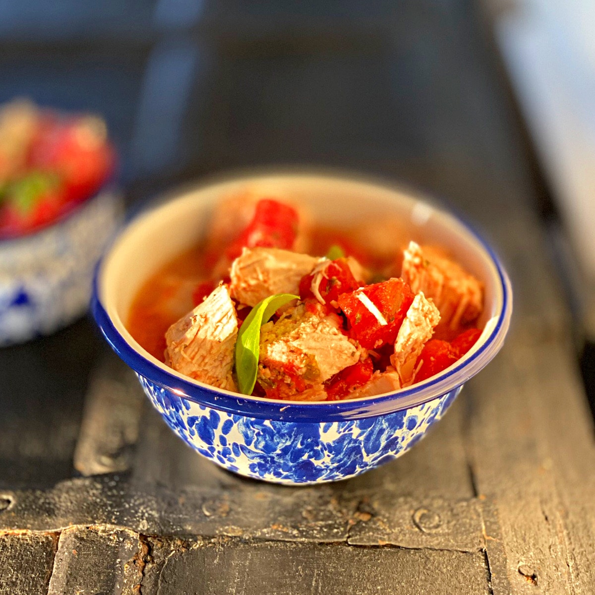 a bowl of finished tomato basil chicken with a blue rim