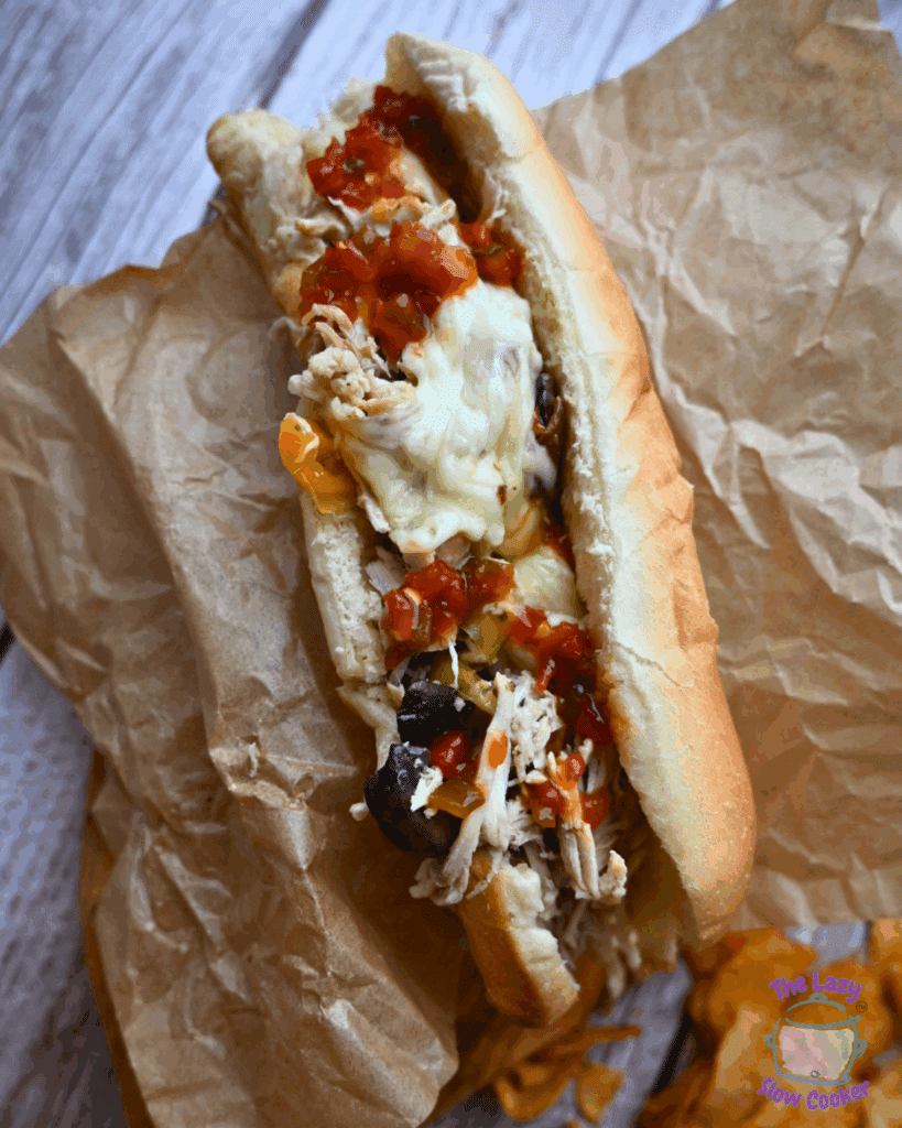 chicken cheesesteak sandwich with toppings on a wooden board