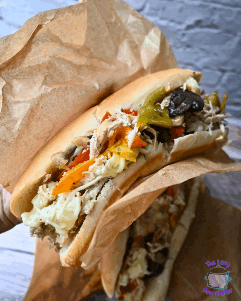 chicken cheesesteak sandwich with toppings on a wooden board