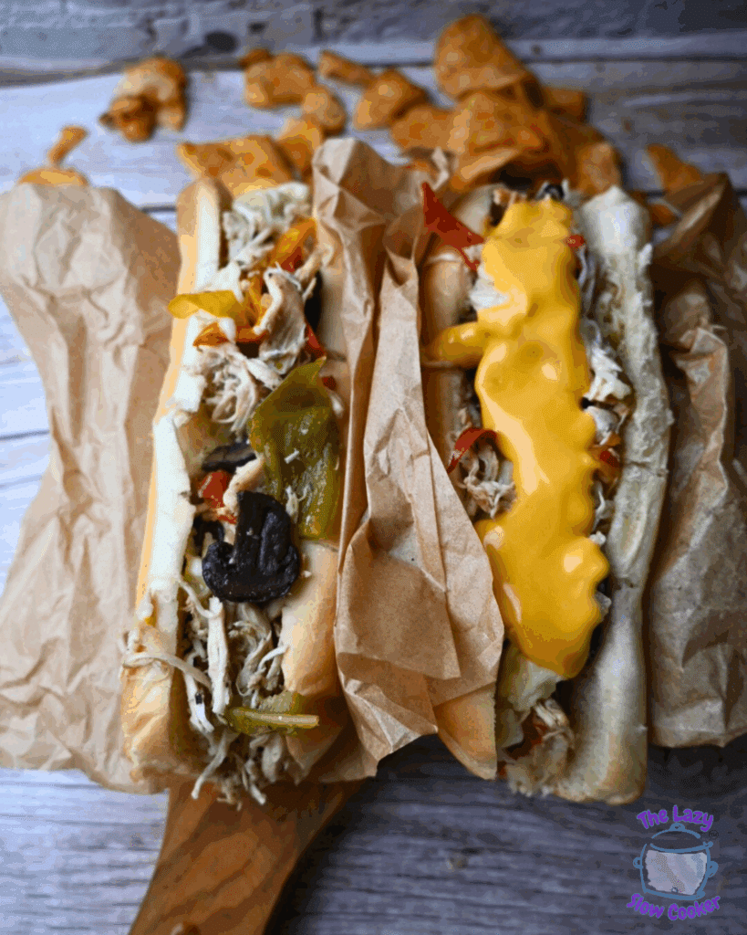 two chicken cheesesteaks with toppings on a wooden board