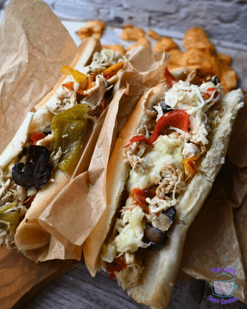 two chicken cheesesteaks with toppings on a wooden board