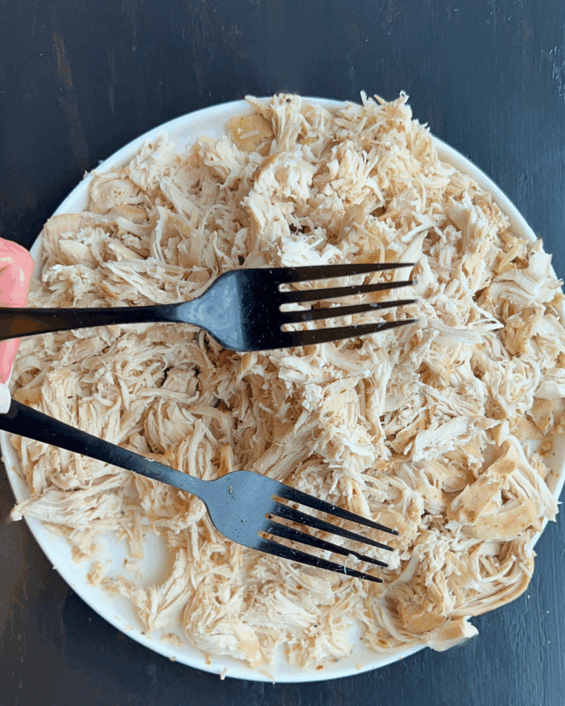 shredded crockpot chicken on a plate with two forks