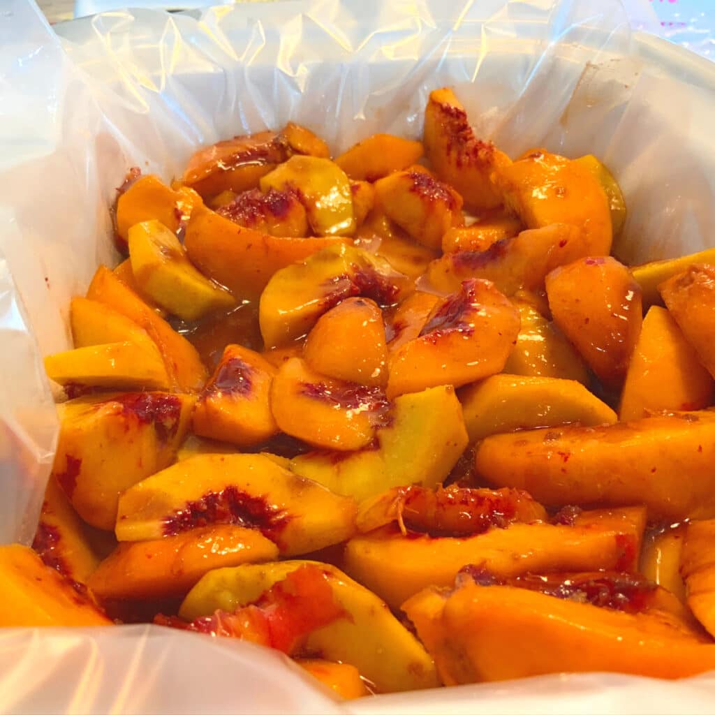 peaches that are sliced and mixed with various ingredients in slow cooker prior to topping being added