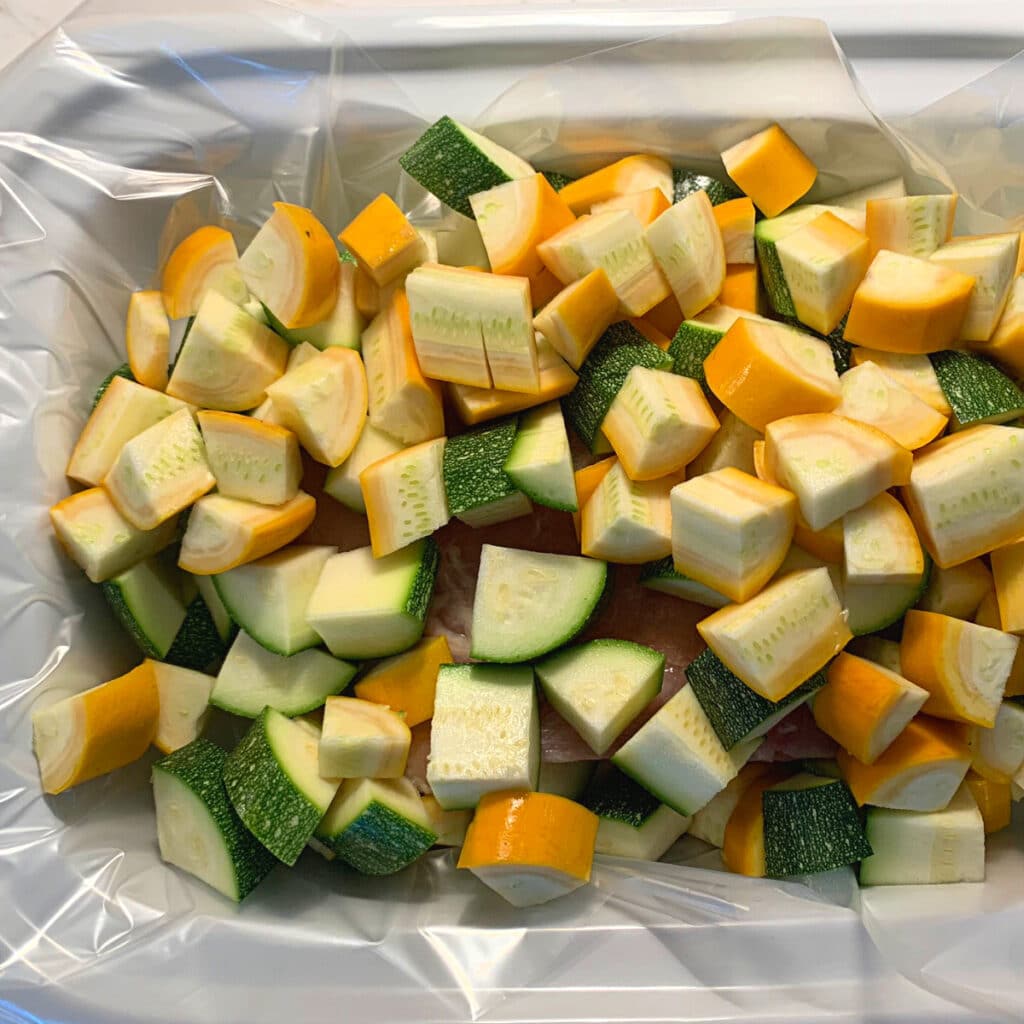 Summer squash and zucchini cut in chunks in a white slow cooker