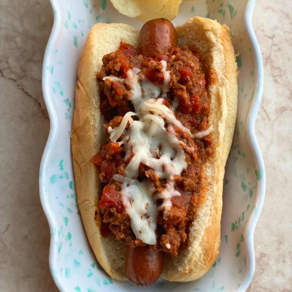 Close up of a chili dog with melted cheese