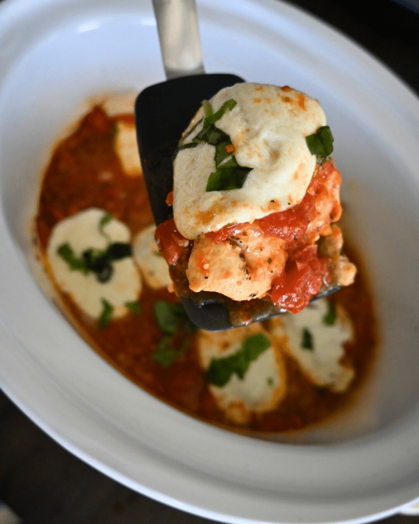 chicken caprese on a spatula over a slow cooker full of the same