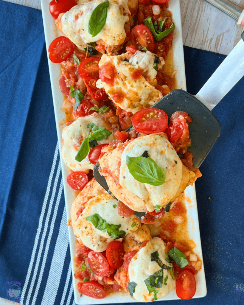 chicken caprese on a spatula over a serving plate full of the same