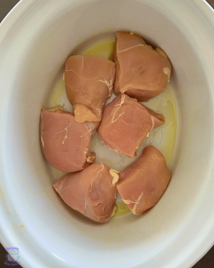 halved chicken breasts in a greased slow cooker
